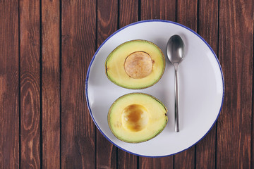 Plate with fresh avocado on wooden background, top view