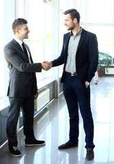  two businessmen shaking hands in office