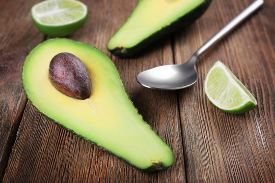 Fresh avocado with lime on wooden background
