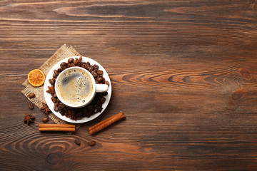 Cup of coffee with spices on wooden table, top view