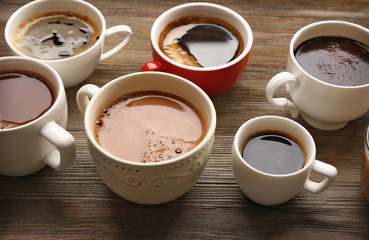 Different cups of coffee on wooden background