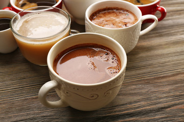 Different cups of coffee on wooden table closeup