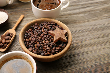 Coffee beans and cups on wooden table closeup