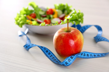 Apple and measuring tape on wooden table closeup