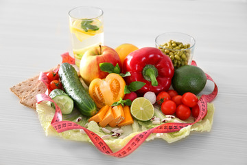 Fresh fruits, vegetables and measuring tape on wooden table closeup