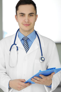 A male doctor with stethoscope holding a clipboard, close-up