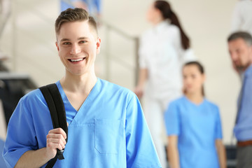 Smiling young male student with backpack, indoors
