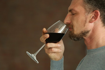 Handsome middle-aged man tasting red wine, close-up