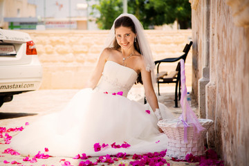 pretty young girl in a wedding dress sitting rose petals