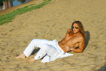 half-naked Fitness model man with sunglasses posing on the beach