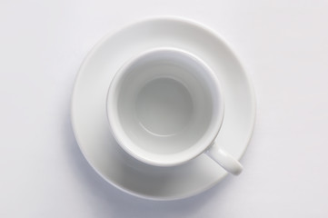 Empty clear coffee cup on saucer against white background, top view