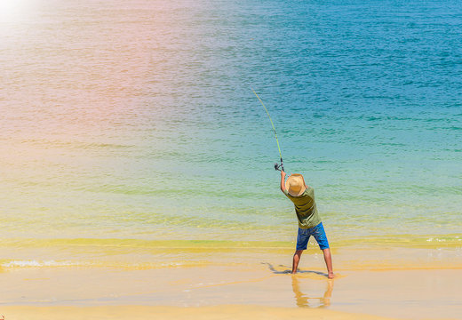 Young boy fishing rod on sunny beach - Powered by Adobe