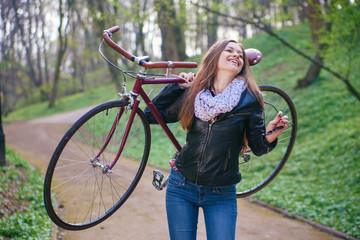 Beautiful young woman with vintage bicycle in a park