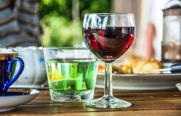 Glass of red vine,coffee and water in table in summer garden