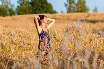 romantic girl in a field of wheat ears at sunset. Portrait of beautiful young woman  in the field