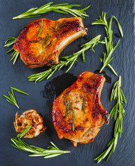 Roasted pork steaks on black stone background. Top view.