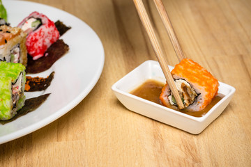 Sushi roll made dish assorti. Chopsticks with roll, nut souce