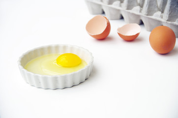 Eggs yoke and shell with egg carton in white background