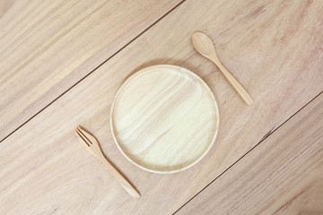 Empty round wooden plate, spoon and bowl on wood table background