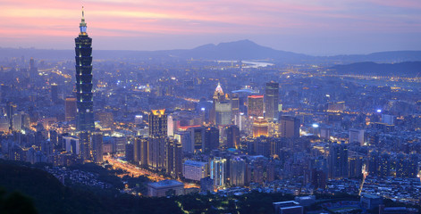 Obraz premium Panorama lotnicza ruchliwego Tajpej o zmierzchu, z widokiem na wieżę Taipei 101 w centrum miasta i rzekę Tamsui oraz odległe góry w tle ~ Niebieska i ponura wieczorna sceneria Tajpej