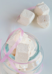 White marshmallows in glass jar on white table
