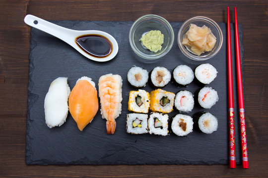 Sushi on flat slate on a wooden table seen from above