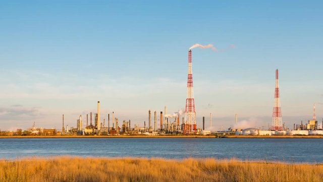 Panning timelapse sequence of a large oil refinery in the harbor of Antwerp, Belgium with blue sky and warm evening light.
