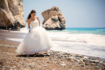 Fototapeta na wymiar outdoor portrait of young beautiful woman bride in wedding dress on beach. Petra tou Romiou - Aphrodite's Rock.