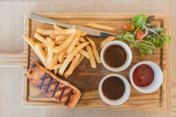 grilled salmon steak with salad and french fries