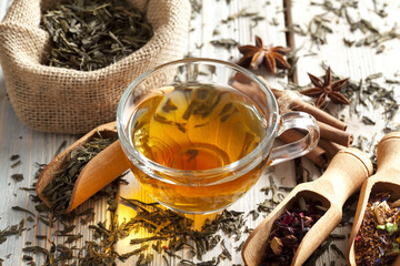 Cup of tea and mix of assorted tea leaves on wooden table