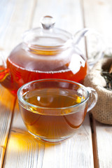 Cup of tea, teapot and dried tea leaves on wooden planks