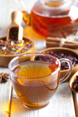 Cup of tea, teapot and mix of assorted tea leaves on wooden tabl
