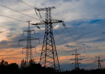 Electricity pylons and lines at dusk at sunset.