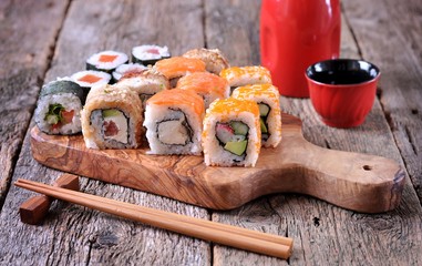 Homemade sushi with salmon, smoked eel, curd cheese and vegetables on a wooden background