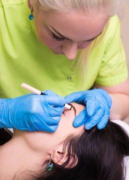 beautician preparing young woman for permanent eyebrow make up p