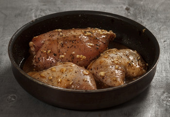 Raw chicken meat in marinade in frying pan ready for cooking