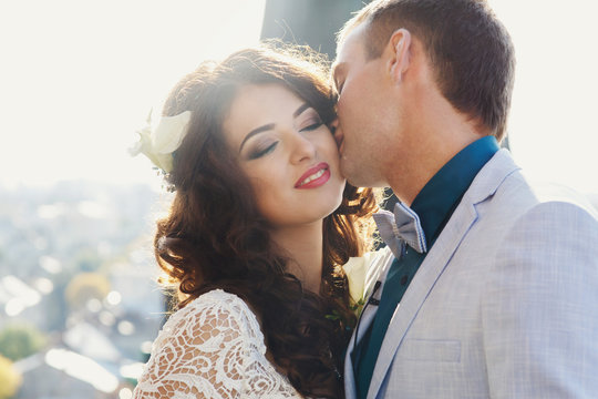 Fiance kisses a bride while wind is playing with her curly hair