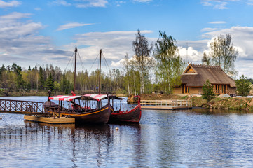 Wooden summerhouse on small island and sailing boats near small pier at river Daugava