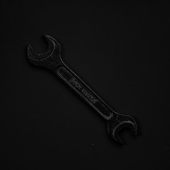 Black & white wrench isolated on black background. Symbolic repa