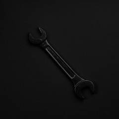 Black & white wrench isolated on black background. Symbolic repa