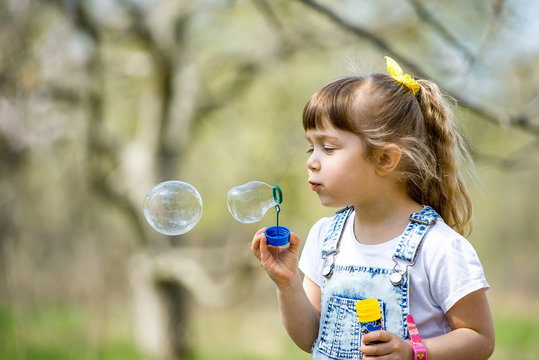 little girl inflates soap bubbles