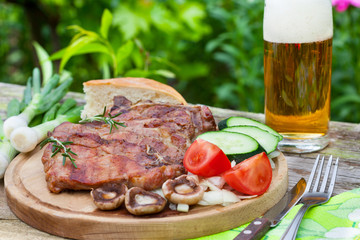 Grilled steaks and vegetable salad with glass of beer