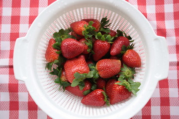 Close-up view of washed strawberries reflecting in a white pot