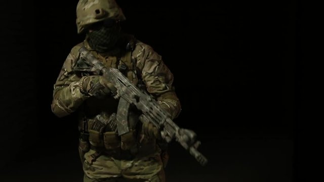 Soldier in camouflage with a gun is moved in the darkness