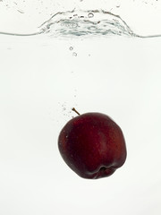 dropping red apple on clear water