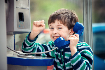 Cute little boy talking on the public phone