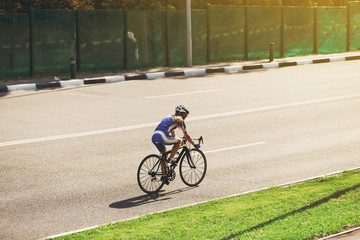 Female cyclist rides a racing bike on road