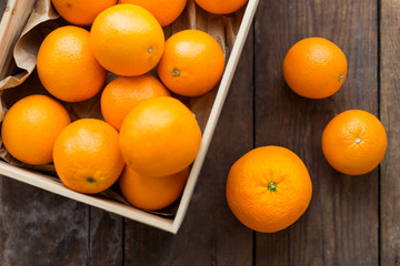 Box full of fresh oranges. Fruit harvest on old rustic wooden background.