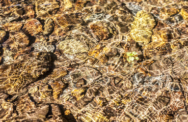 Translucent water waves over brown pebbles