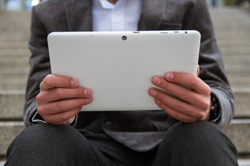 Businessman resting from work and while sending messages and talking with his white tablet.